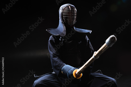 Fototapety Kendo  zawodnik-kendo-w-kasku-trzymajacy-bambusowy-miecz-na-czarno