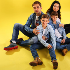  Portrait of happy  family on yellow background with twins and sitting 