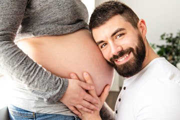 A Beautiful pregnant woman and her handsome husband close look t the belly