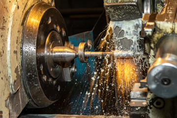 Closeup big industrial CNC lathe machine cutting the steel rod in wirking with sparks