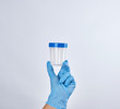 © nndanko - hand in a blue sterile glove holds a plastic container for collecting analyzes