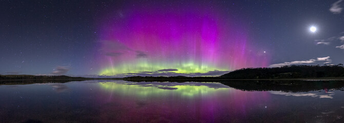 A spectacularly bright and colourful display of the Aurora Australis or Southern Lights with reflection in water