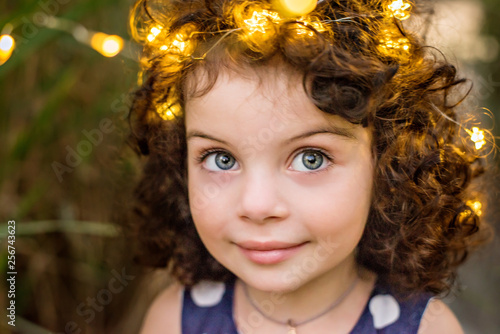 A Beautiful Little Girl With Big Eyes And Dark Curly Hair