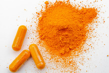 Alternative Medicine, Antioxidant Food And Herbal Remedy Concept Theme With Macro Close Up On Supplement Pill Of  Curcumin Or Turmeric With A Heap Of The Spice In Dry Powder Form In The Background