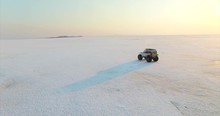 White Swamp Buggy Is Driving On Ice Of Huge Frozen Lake Hanka In The Evening. Aerial. Far East Of Russia