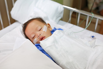 baby boy age about 1 year old sleeping on patient bed with getting oxygen via nasal prongs to assure