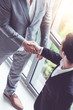 © InfiniteFlow - Businessman handshake with another businessman partner in modern workplace office. People corporate business deals concept.