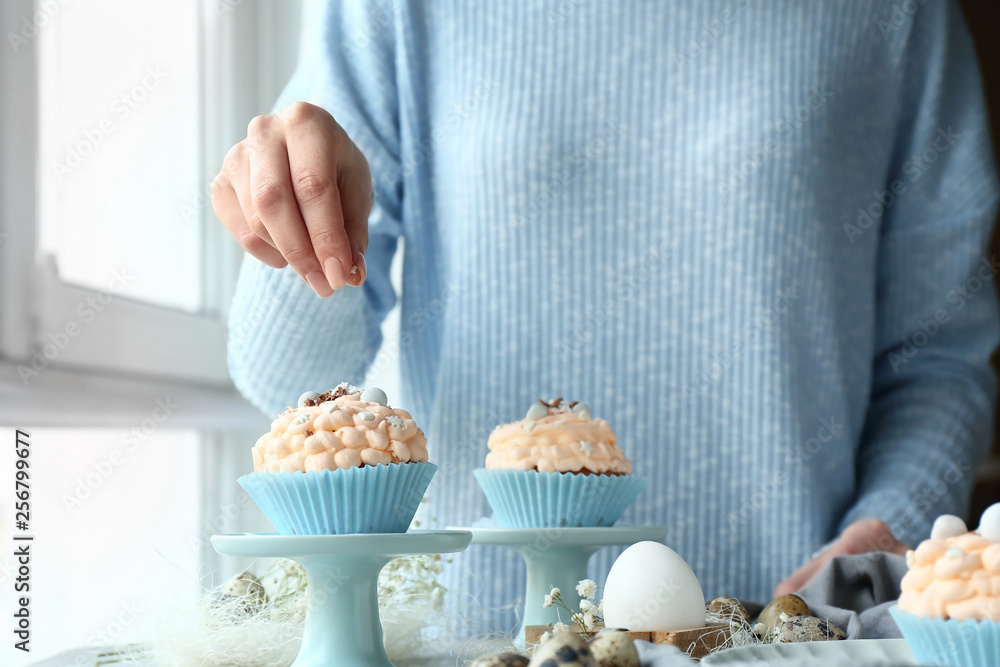 Woman decorating tasty Easter cupcakes