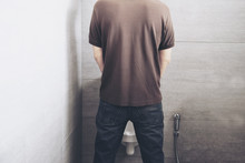Man Is Standing Pee In A Toilet - Healthcare Urinal Concept
