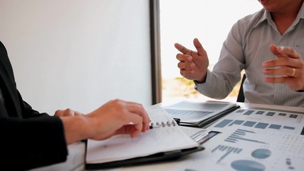 Wall Mural - Two businessmen shaking hands are jointly analyzing the budget and signing the contract together.