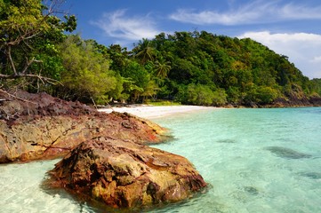 Volcanic rock in turquoise sea and tropical beach on Koh Chang Island, Thailand.