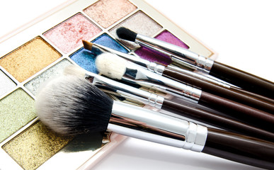 Various set of professional makeup brushes and palette of colourful eye shadows isolated