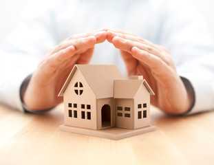 Poster - Property insurance. House miniature covered by hands. 