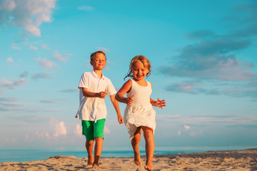 Wall Mural - happy little boy and girl running on beach