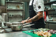 © Friends Stock - I love Italian food Side view of young chef's hands with tattoos cooking homemade italian pasta in a restaurant kitchen