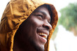 © mimagephotos - Close up happy black man with raincoat outside in rain