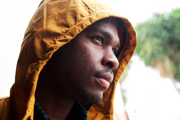 Close up young black man outdoors in the rain with raincoat