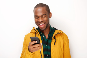 smiling young black man looking at mobile phone against isolated white background
