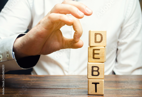 Fotografía Businessman removes wooden blocks with the word Debt