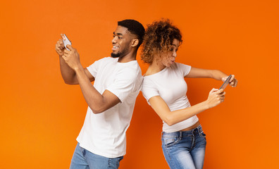 Excited young man and woman playing together on smartphones