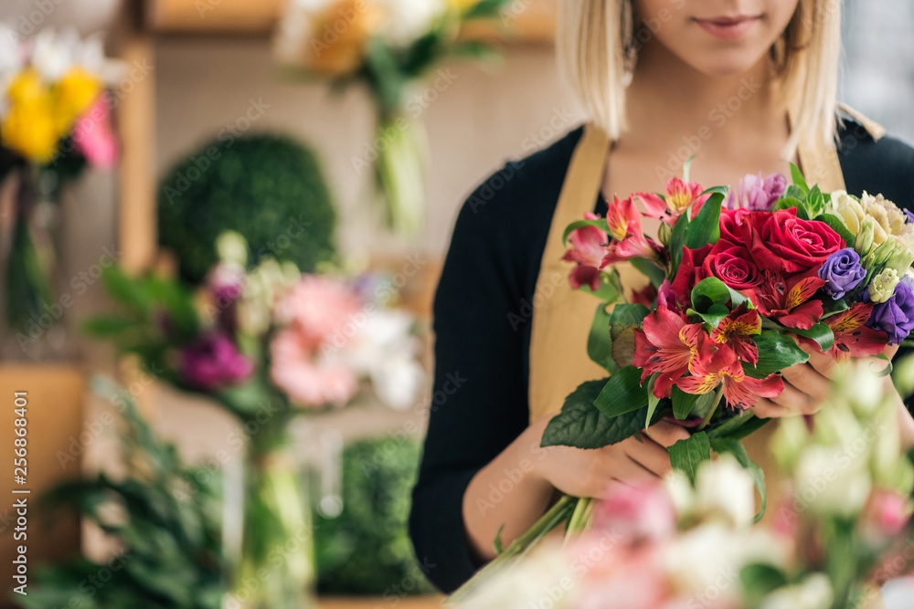 Cropped view of florist in apron holding bouquet in flower shop - obrazy, fototapety, plakaty 