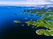 Aerial view of blue lakes and green forests on a sunny summer day in rural Finland.