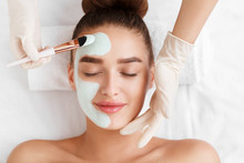 Beautician Applying Clay Face Mask On Woman Face