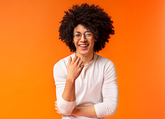 Wall Mural - Cute carefree black curly guy laughing on orange background