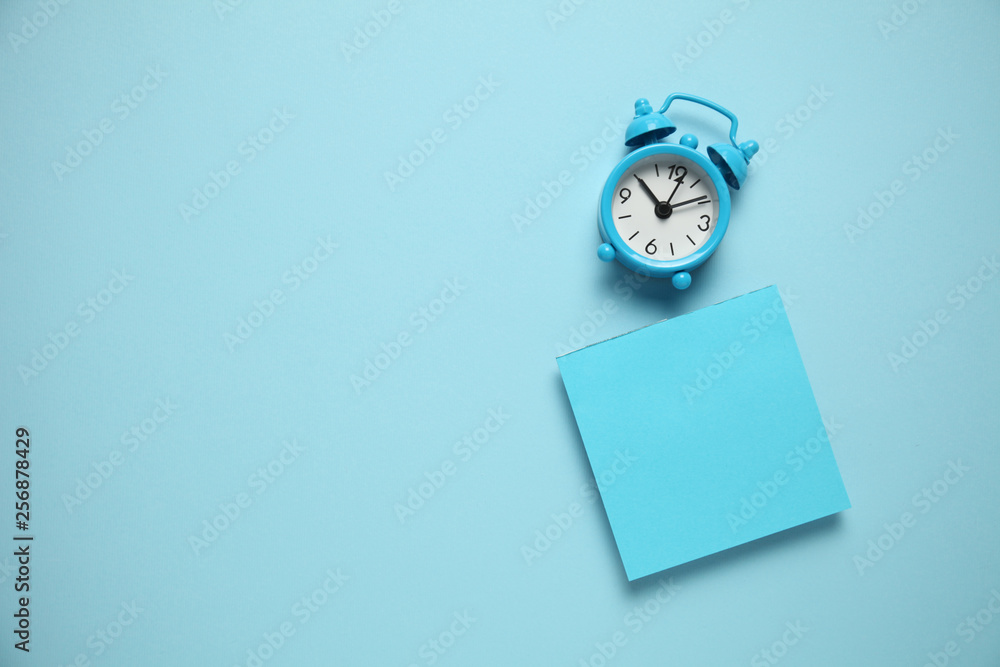 Blue alarm clock and a reminder note. Time management concept. Copy space for text. - obrazy, fototapety, plakaty 