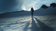 Hiker With Backpack Climbing Top Of Mountain, Mountaineering Concept. Man Walking Snow, Hiking In Winter. Trekking Adventure, People In Nature Concept. Epic Sunset View Snow Mountain Landscape,