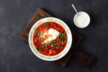 Wall Mural - Traditional  ukrainian russian traditional beet red soup - borscht with sour cream on black stone background. Top view.