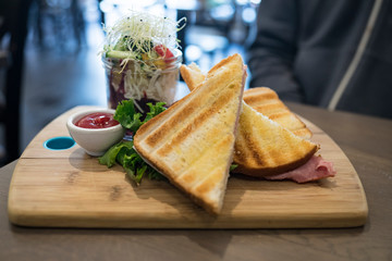 sandwiches ham cheese with salad in jar on a wooden plate