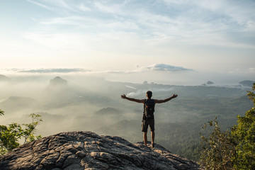 Young hiker on the summit of the mountain expressing joy opening his arms