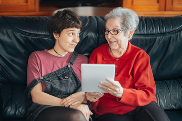 Wall Mural - Granddaughter teaches her grandmother how to use a tablet