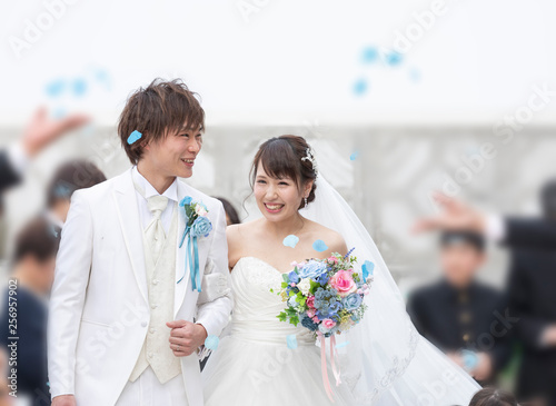 結婚式 フラワーシャワーで祝福される笑顔の新郎と新婦 Wall Mural West Photo