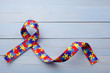 © vetre - World Autism awareness and pride day or month with Puzzle pattern ribbon on blue wooden background.