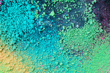 A splatter of green blue natural colored pigment powder on black background.