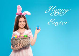 Sticker - Little girl in bunny ears headband holding basket with eggs on color background. Happy Easter