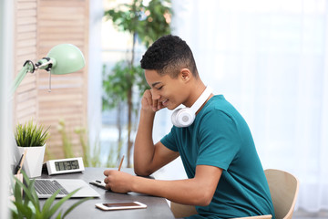 african-american teenage boy doing homework at table in room