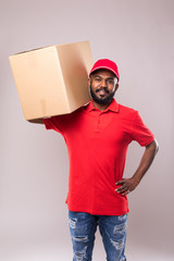 Wall Mural - Side view of young delivery man with box isolated gray background