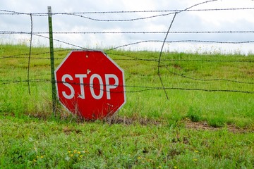 Stop Traffic Sign on a barbwire fence in a field.