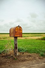 An Old Rusty Mailbox In A Field.