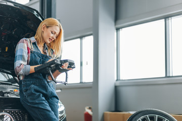 Wall Mural - pleasant blond girl using an automotive diagnostic scanner, close up photo. copy space