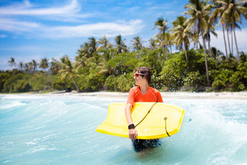 Child surfing on tropical beach. Surfer in ocean.