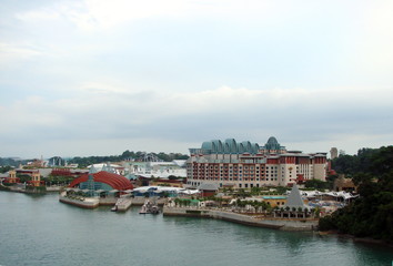 Landscape from the top deck of a cruise ship with amazing buildings on the seafront promenade of a seaside city on the background of snow-white clouds in the sky.