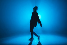 A Dark Silhouette Of A Singer On The Stage, Dancing Alone During Performance On Dark Blue Neon Background With Smoke And Lights.