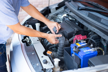 Car engineer is taking care of engine filter in the garage.