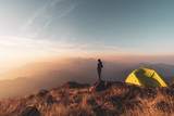 Fototapeta  - Young man traveler looking landscape at sunset and camping on mountain, Adventure travel lifestyle concept