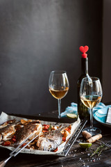 Wall Mural - dinner concept for two. two glasses of white wine, baked fish.