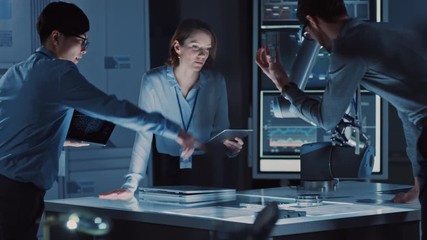 Leinwandbilder - Diverse Team of Engineers with Laptop and a Tablet Analyse and Discuss How a Futuristic Robotic Arm Works and Moves a Metal Object. They are in a High Tech Research Laboratory with Modern Equipment.